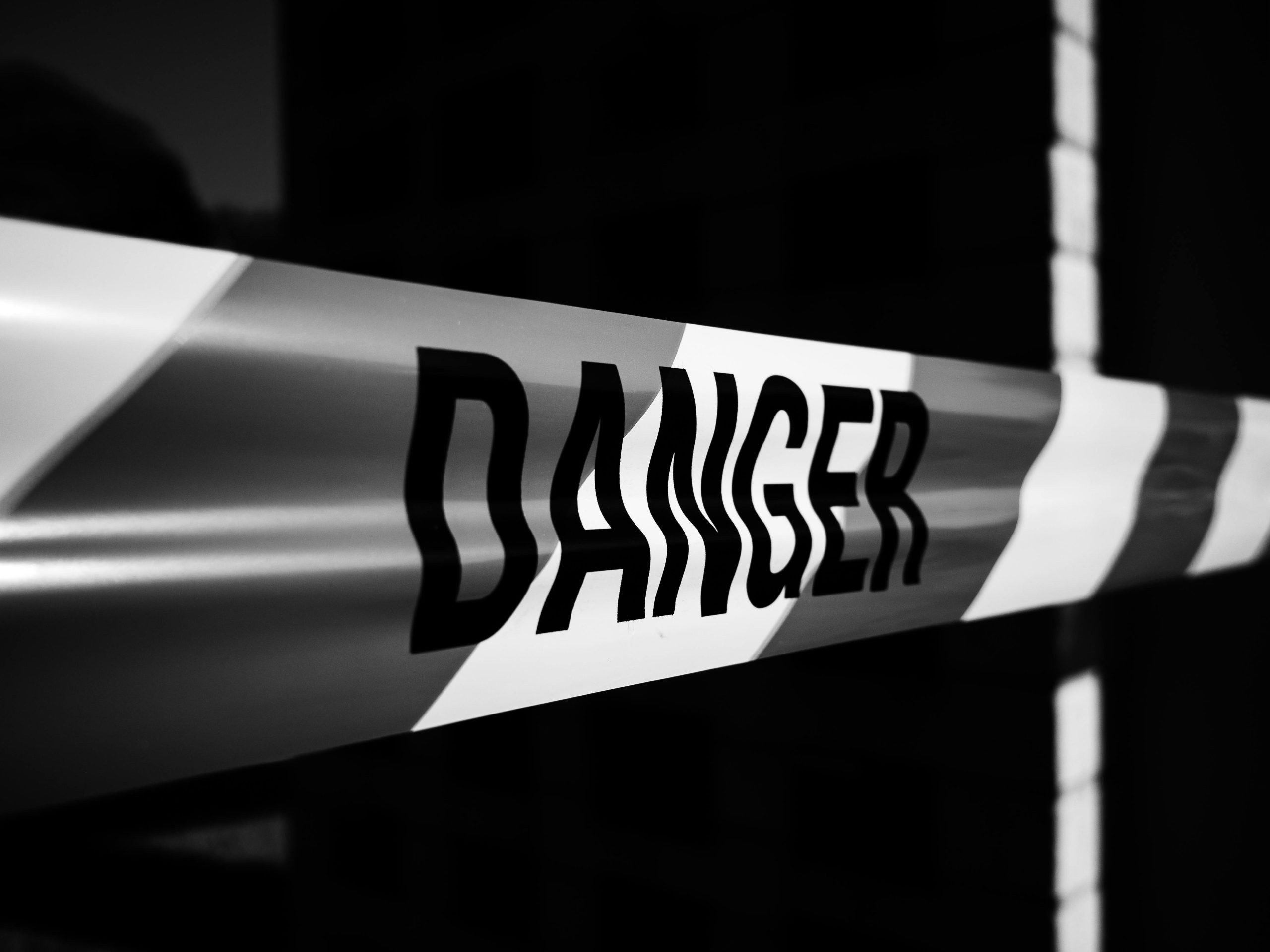 Close-up of a danger tape in black and white, emphasizing caution and warning.