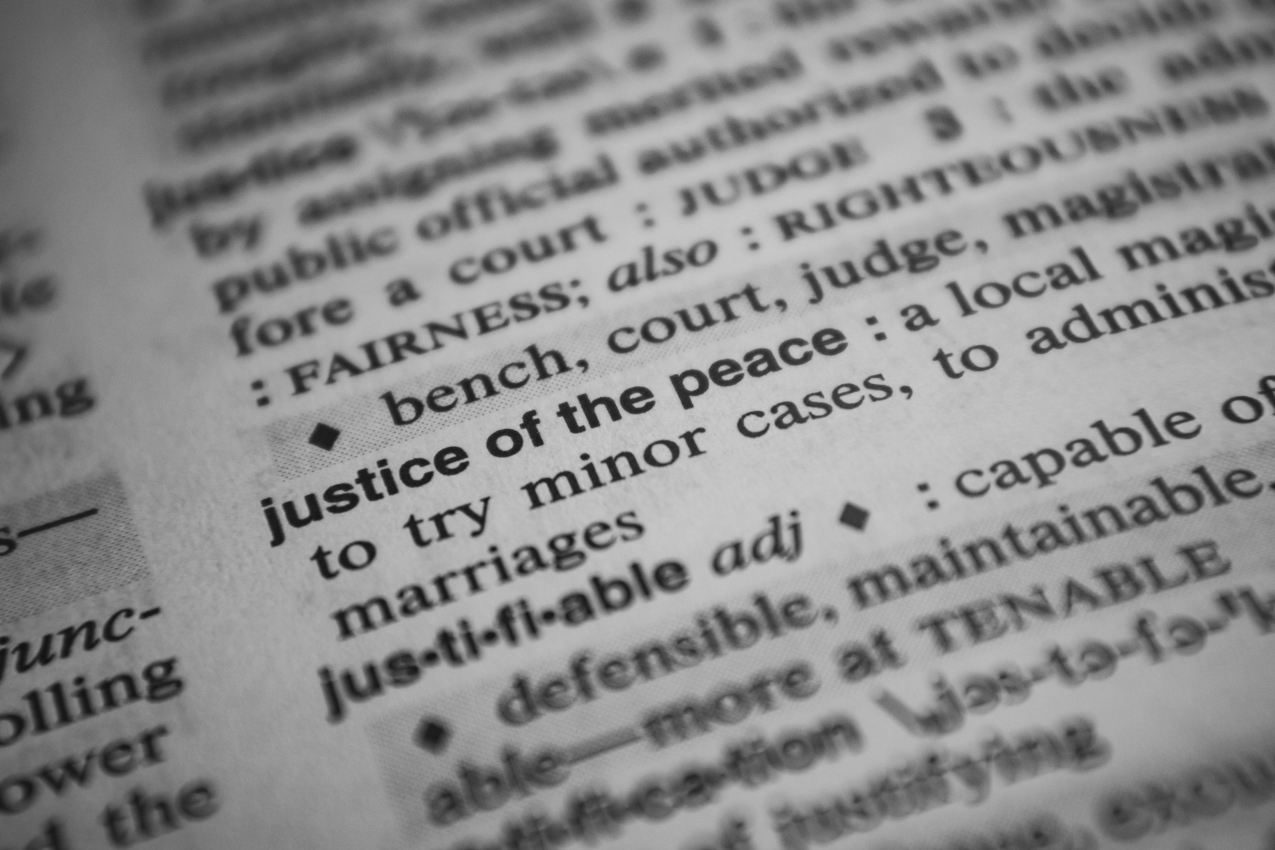 Close-up image of the definition 'justice of the peace' in a dictionary.