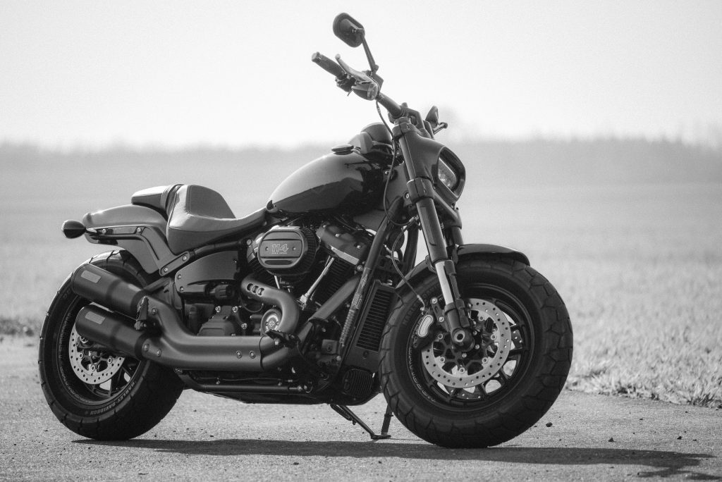Black and white image of a Harley Davidson motorcycle parked on a road, showcasing its design.