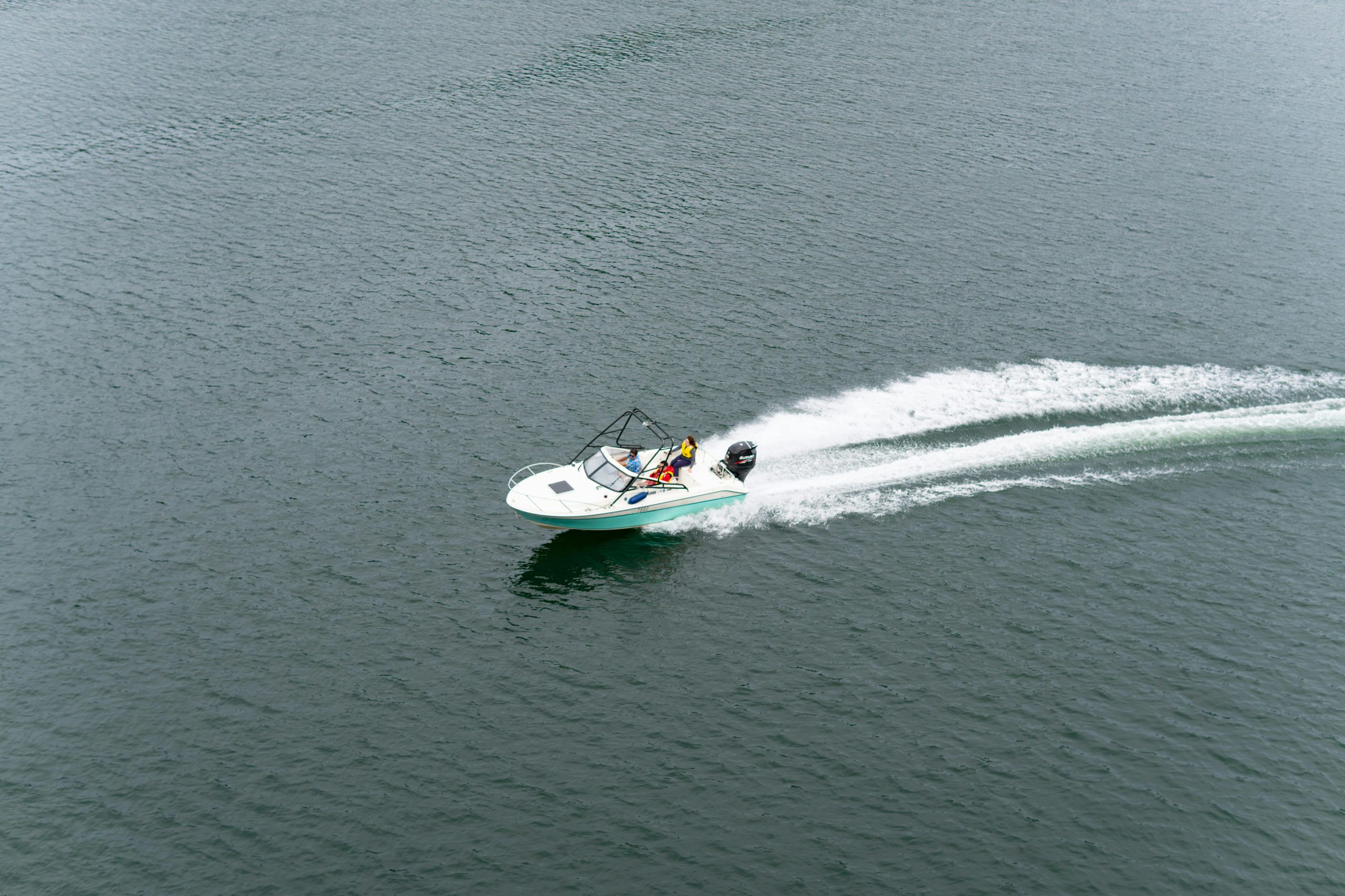 High-angle view of a motorboat speeding across a peaceful lake, leaving a trail of white wake in Japan.